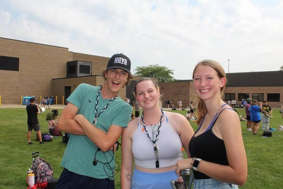 Image 1 of 2 Three students standing outside in summer clothes smiling for a picture